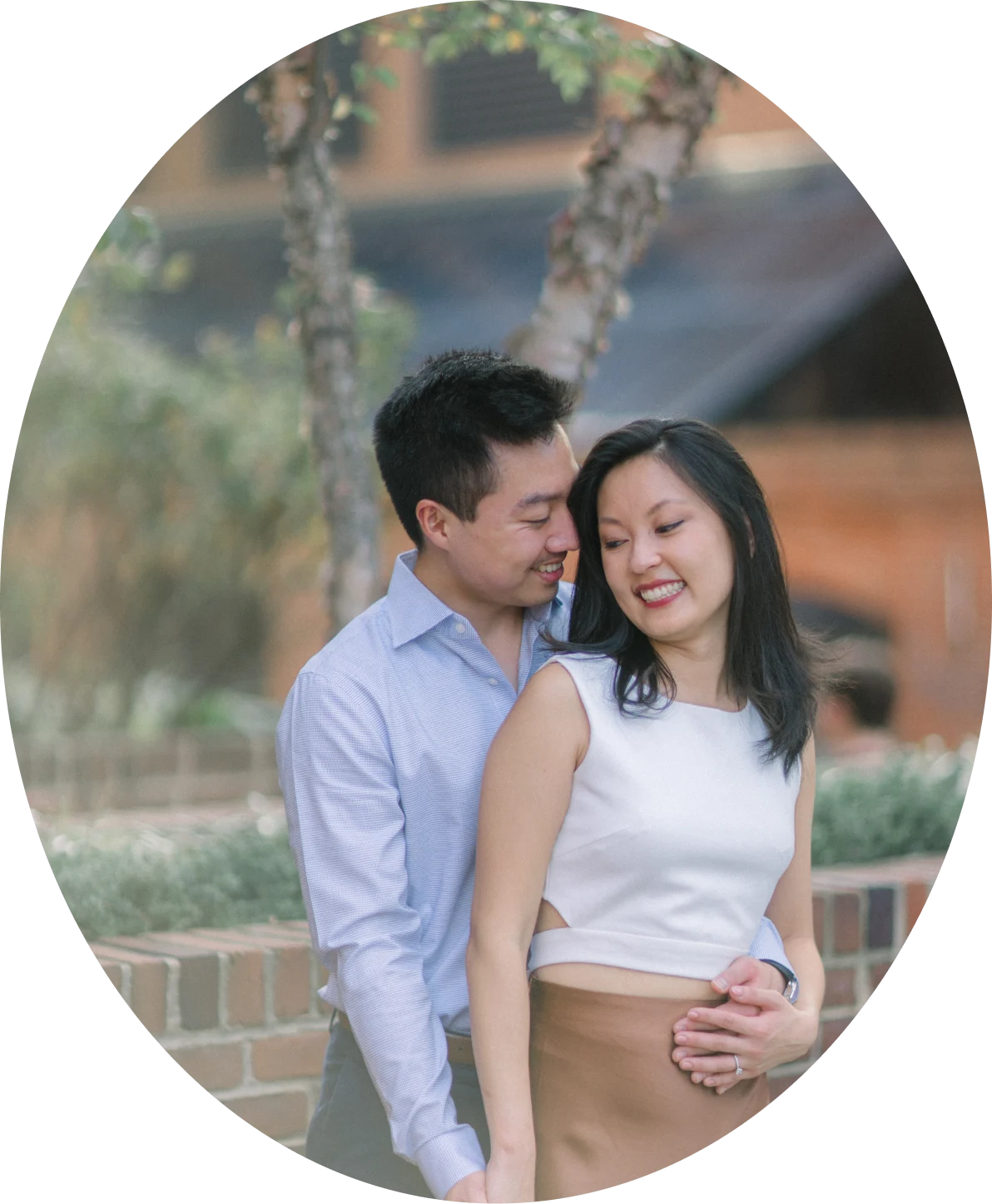 The couple embracing in front of a brick wall.